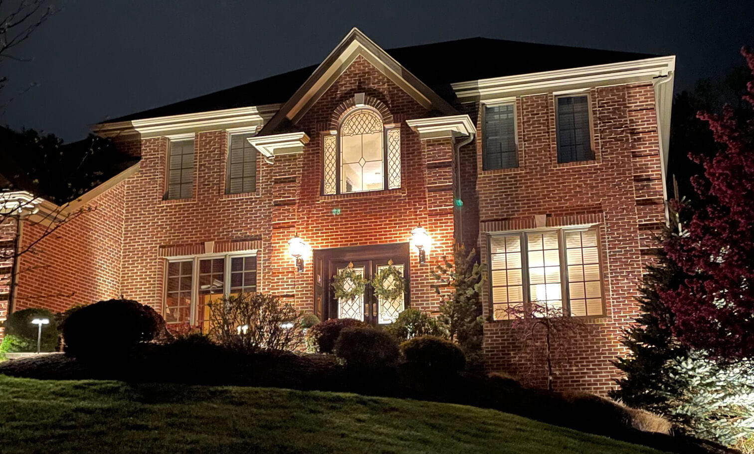 Brick home illuminated with elegant outdoor lighting at night